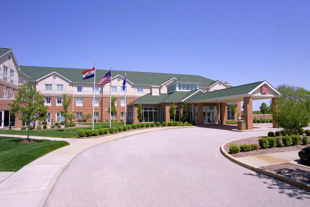 un grand bâtiment avec des drapeaux en face d'une allée. dans l'établissement Hilton Garden Inn St. Louis/O'Fallon, à O'Fallon