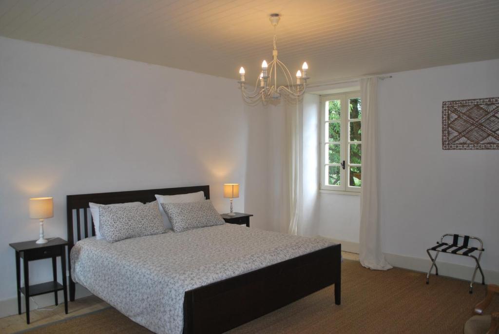 Schlafzimmer mit einem Bett, einem Fenster und einem Kronleuchter in der Unterkunft La ferme de Roquedure in Montfaucon