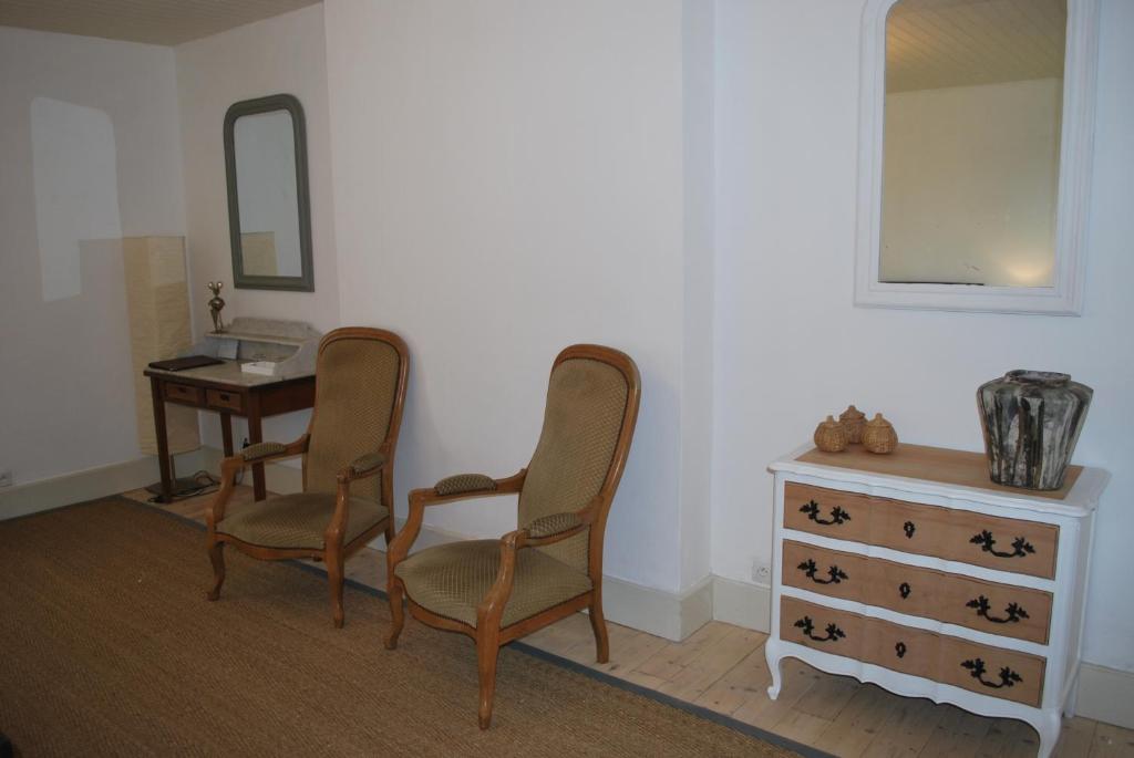 Zimmer mit 2 Stühlen, einer Kommode und einem Spiegel in der Unterkunft La ferme de Roquedure in Montfaucon