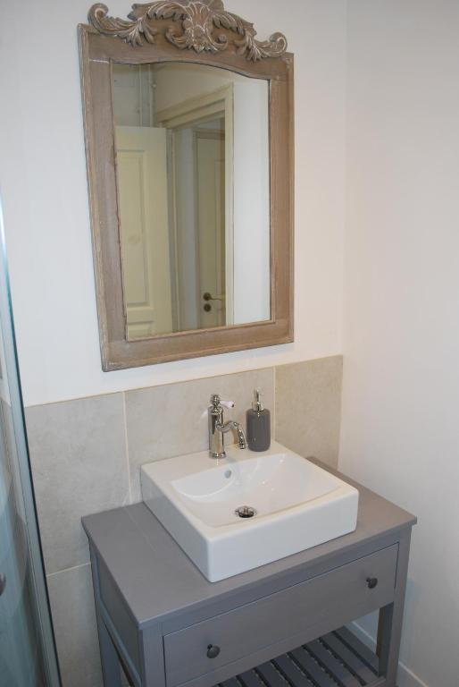 ein Badezimmer mit einem weißen Waschbecken und einem Spiegel in der Unterkunft La ferme de Roquedure in Montfaucon