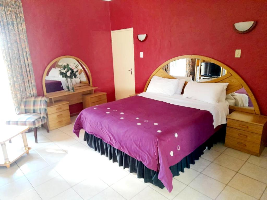 a bedroom with a large bed and a red wall at Rietkuil Country Cottages in Cremin