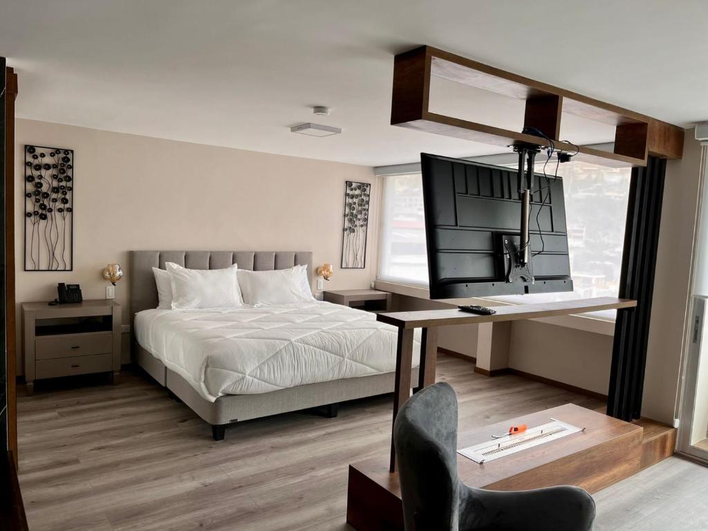 Dormitorio con cama, escritorio y TV en Hotel Ambato, en Ambato