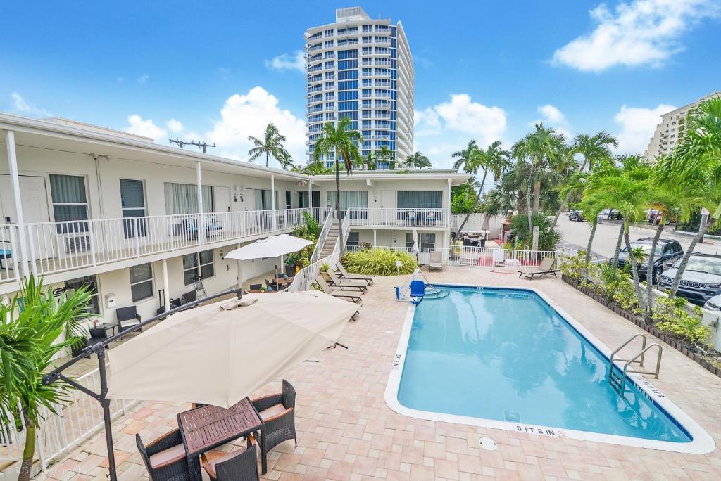 a swimming pool with a umbrella and a building at Soleado Hotel in Fort Lauderdale