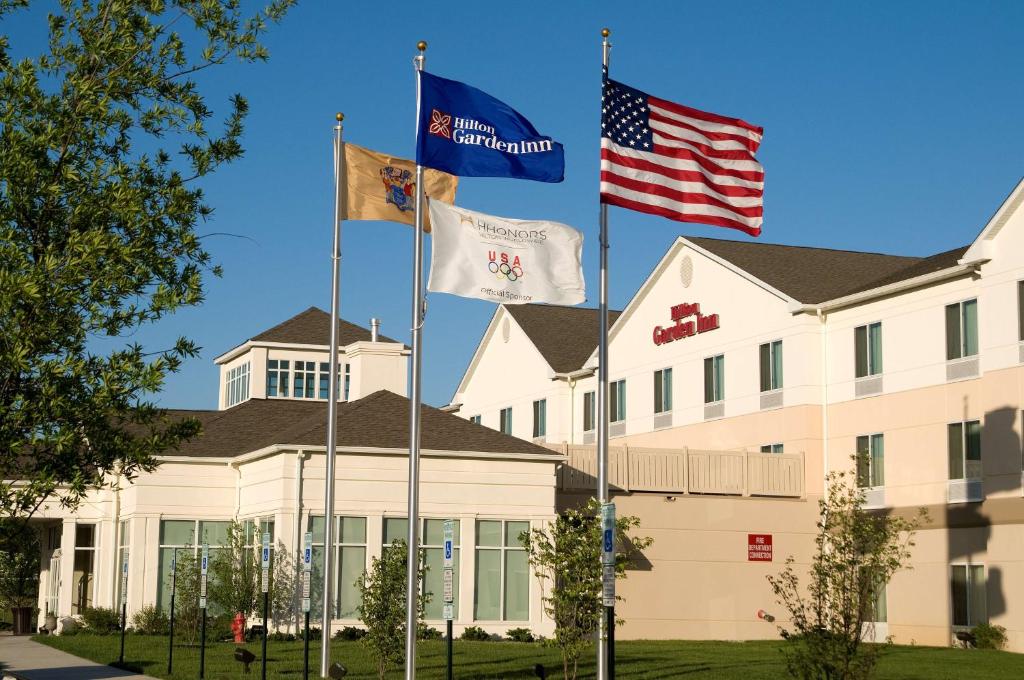 três bandeiras a voar em frente a um edifício em Hilton Garden Inn Mount Holly/Westampton em Westampton Township