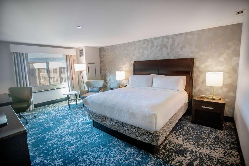 Cette chambre comprend un lit et une grande fenêtre. dans l'établissement Hilton Garden Inn Bethesda Downtown, à Bethesda
