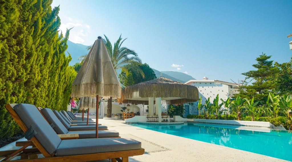 eine Gruppe von Stühlen und Sonnenschirmen neben einem Pool in der Unterkunft Kassandra Boutique Hotel in Oludeniz