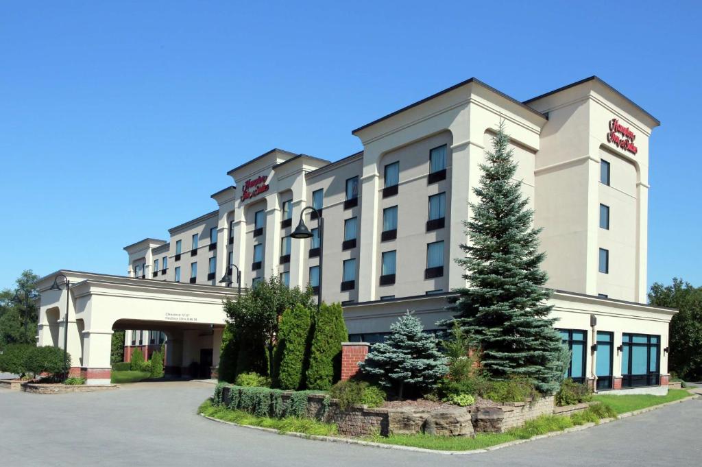 un hôtel avec un arbre devant un bâtiment dans l'établissement Hampton Inn & Suites Laval, à Laval