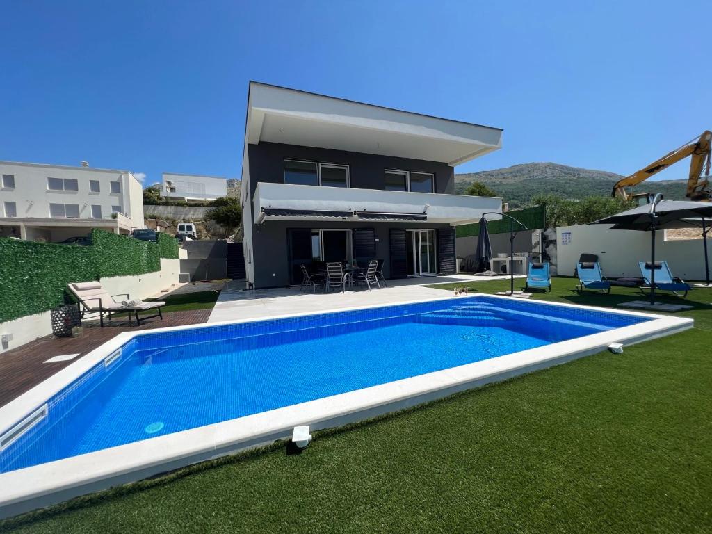 a villa with a swimming pool in front of a house at Villa La Vie - Podstrana in Podstrana