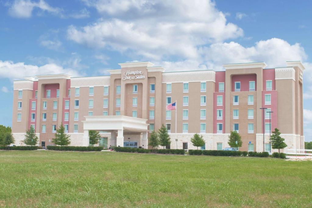 a large building with a grass field in front of it at Hampton Inn & Suites Dallas/Frisco North-Fieldhouse USA in Frisco