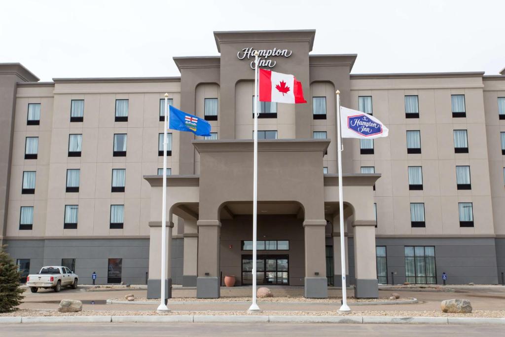 a hotel with flags in front of a building at Hampton Inn by Hilton Lloydminster in Lloydminster