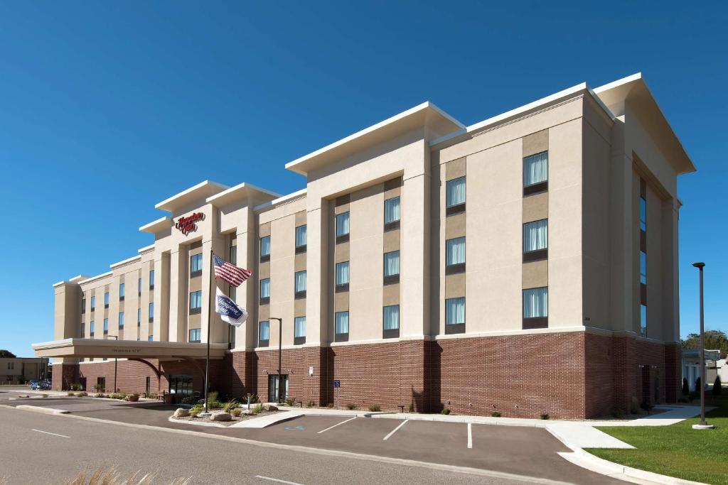 una vista exterior de un hotel con bandera americana en Hampton Inn Kalamazoo, en Kalamazoo