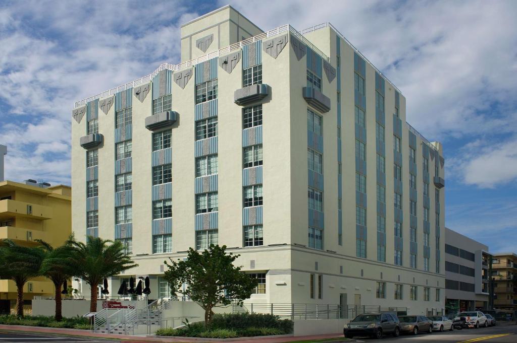 Hilton Garden Inn Miami South Beach في ميامي بيتش: مبنى ابيض كبير فيه سيارات تقف امامه
