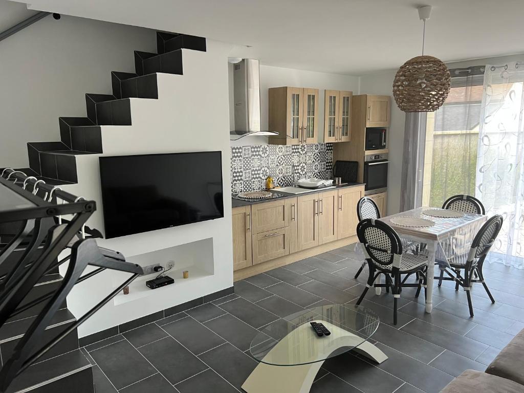 a living room with a table and a tv and a kitchen at la vallées du tuffeau in Bourré