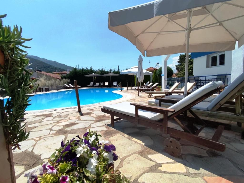 a pool with two lounge chairs and an umbrella at Villa Riviera in Stavros