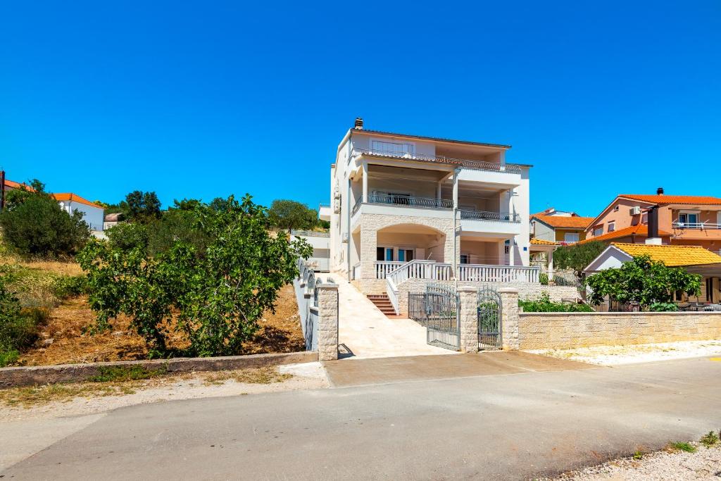 una gran casa blanca con una escalera delante de ella en Apartment Bilice beach, en Bilice