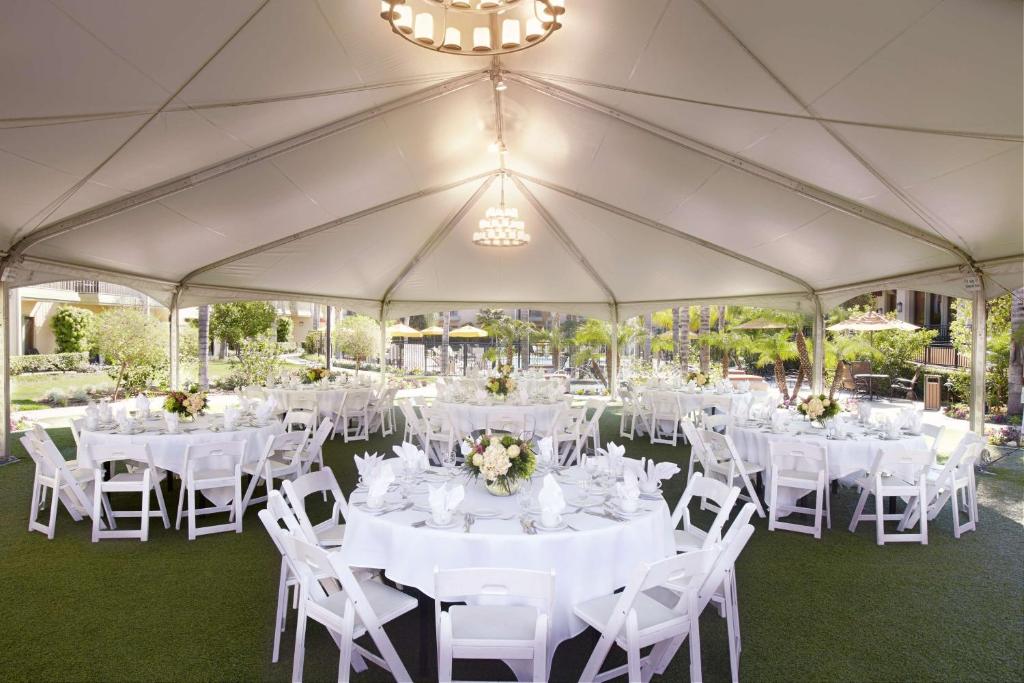 a marquee with white tables and chairs and a chandelier at DoubleTree by Hilton Ontario Airport in Ontario
