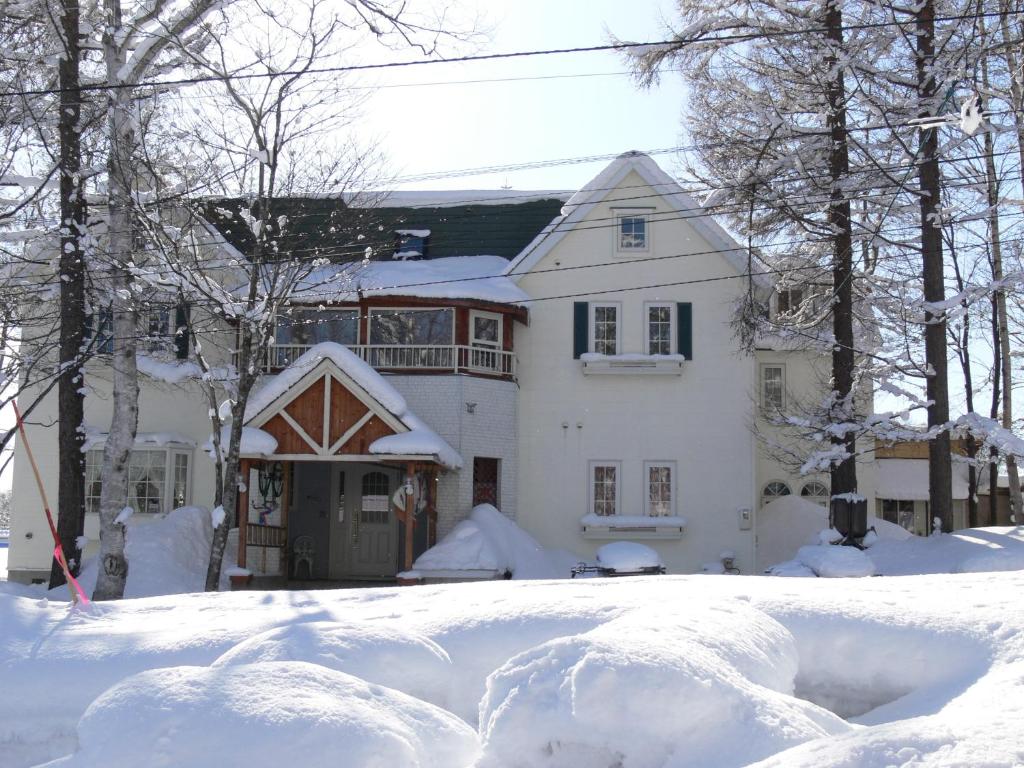 una casa cubierta de nieve con mucha nieve en Pension Locomotion, en Niseko