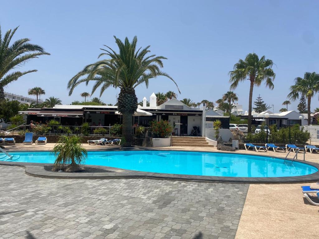 una piscina con palmeras y un complejo en One bedroom bungalow Playa Bastian Costa Teguise, en Costa Teguise