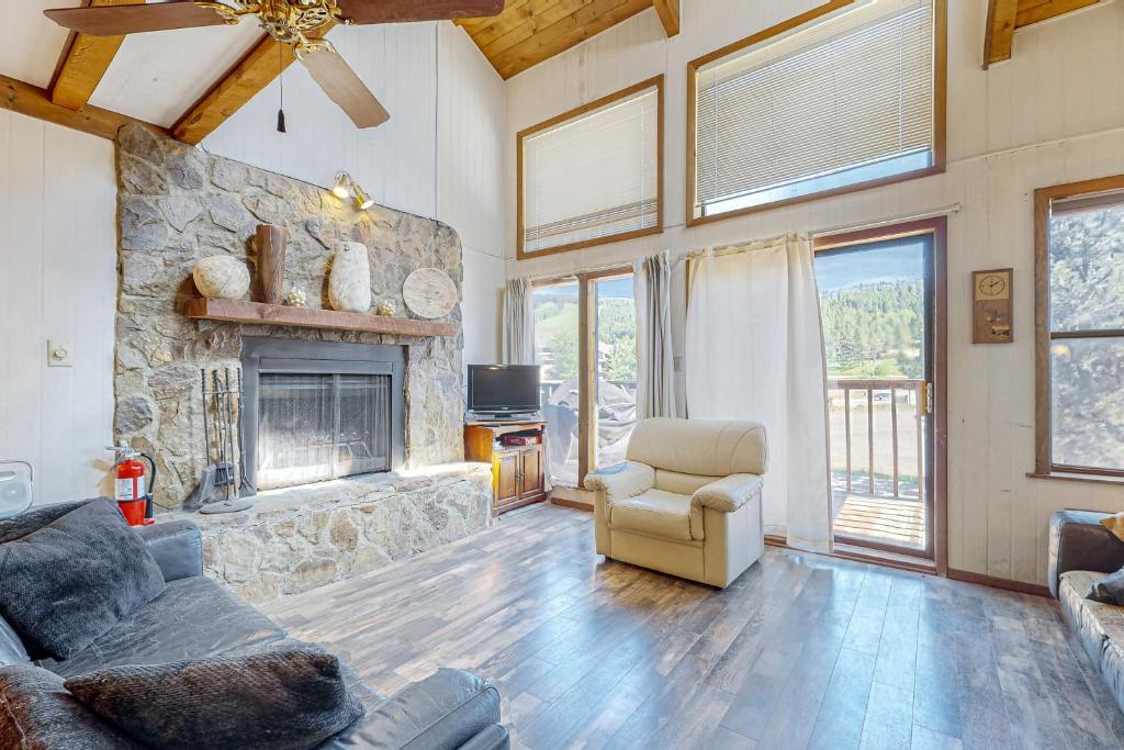 uma sala de estar com uma lareira de pedra e um sofá e cadeira em Timbers Four em Angel Fire