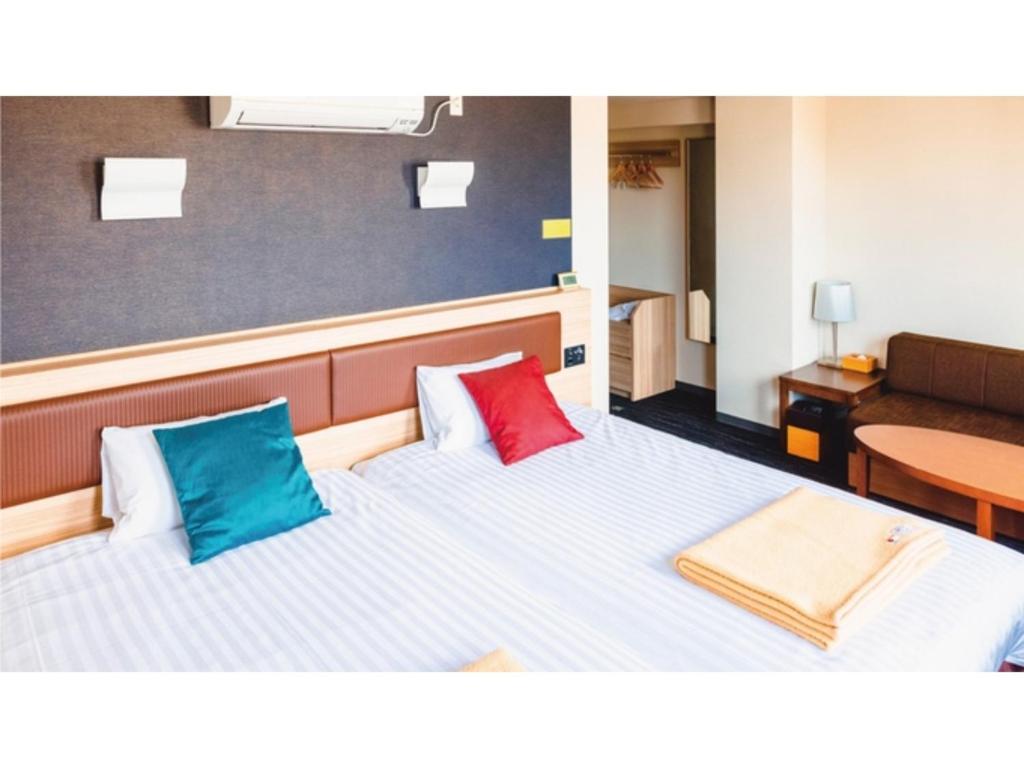 a room with a bed with two colorful pillows at AIRAIKU HOTEL Kagoshima - Vacation STAY 17445v in Aira