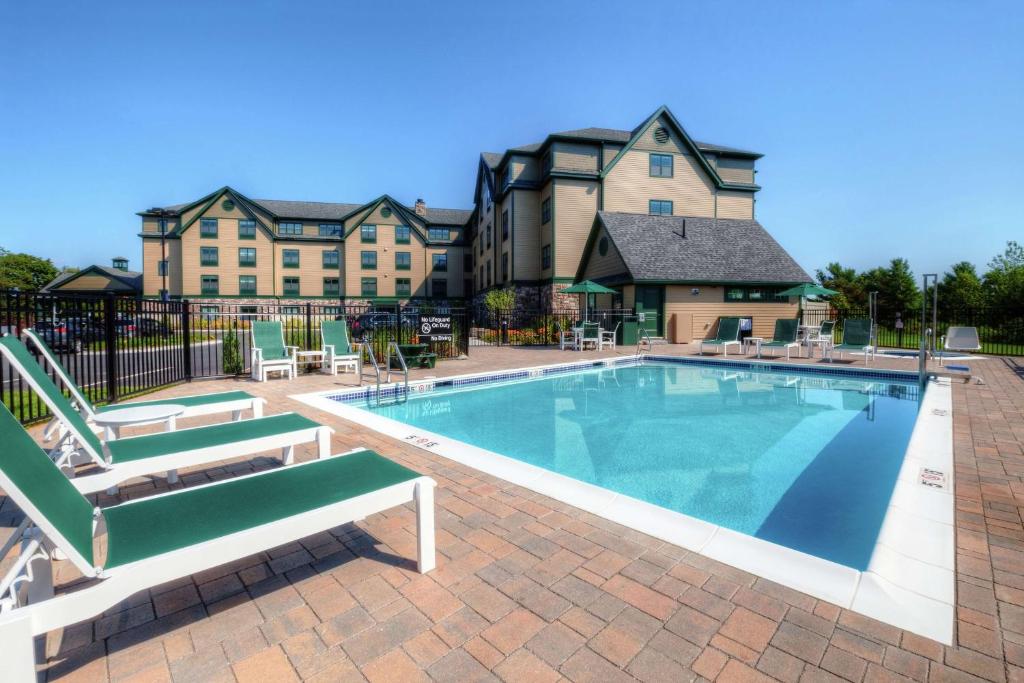 a swimming pool with two chairs and a building at Hampton Inn Bar Harbor in Bar Harbor