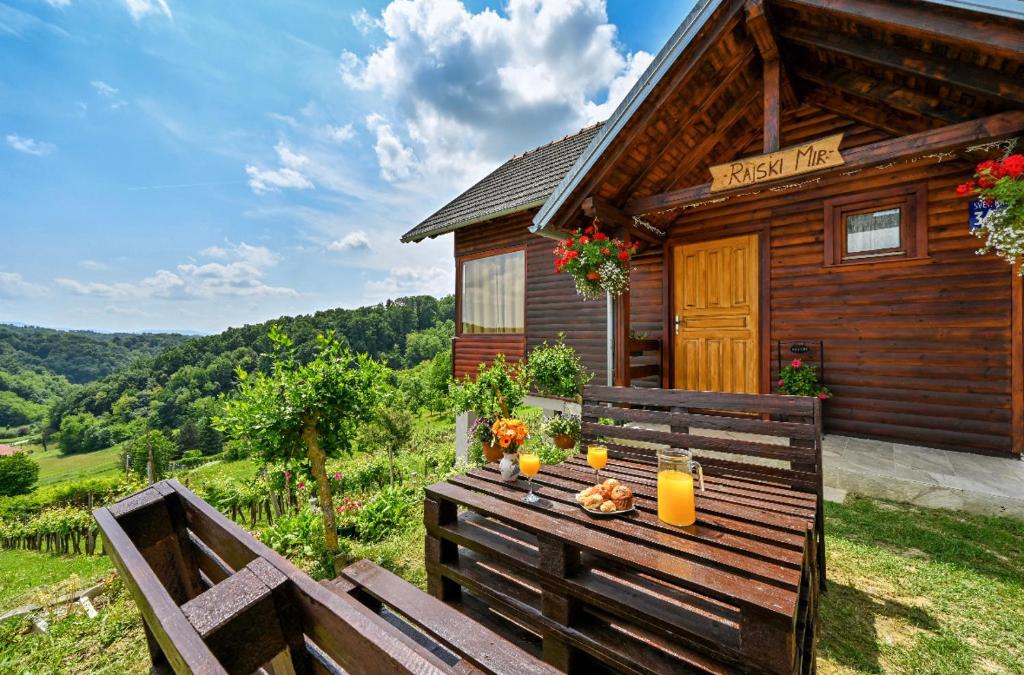 una mesa de picnic frente a una cabaña de madera en Ruralna kuća za odmor RAJSKI MIR en Tuhelj