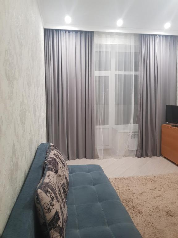 uma sala de estar com um sofá em frente a uma janela em Квартира в центре левого берега Астаны Туран, 46А em Taldykolʼ