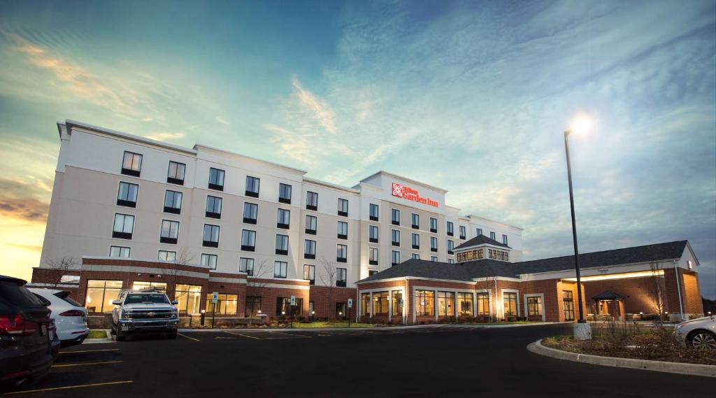 ein großes weißes Gebäude mit Autos auf einem Parkplatz in der Unterkunft Hilton Garden Inn Bolingbrook I-55 in Bolingbrook