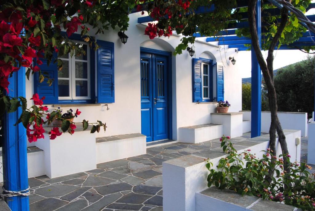 een huis met blauwe deuren en een boom bij Giaglakis Rooms in Platis Yialos Sifnos