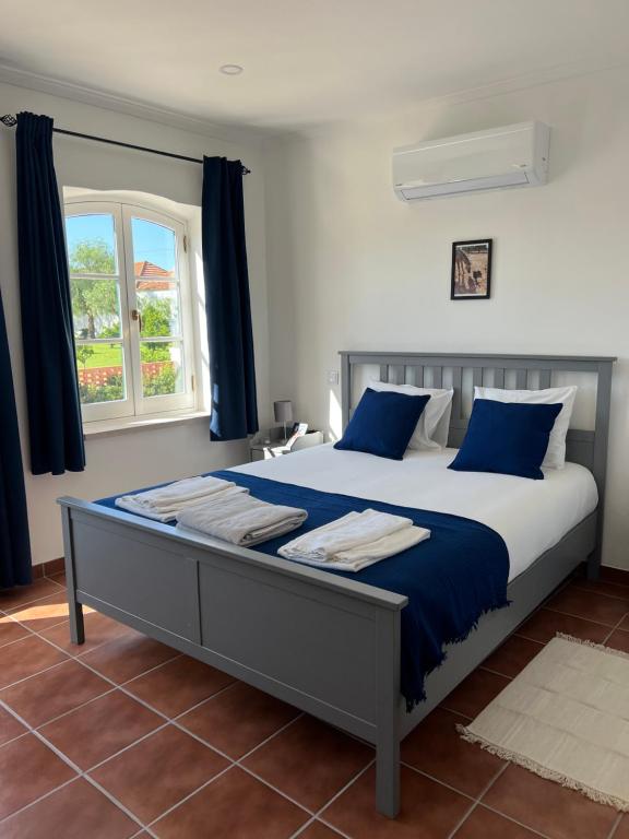 una camera da letto con un grande letto con cuscini blu e una finestra di Quinta da Varzea a Raposa