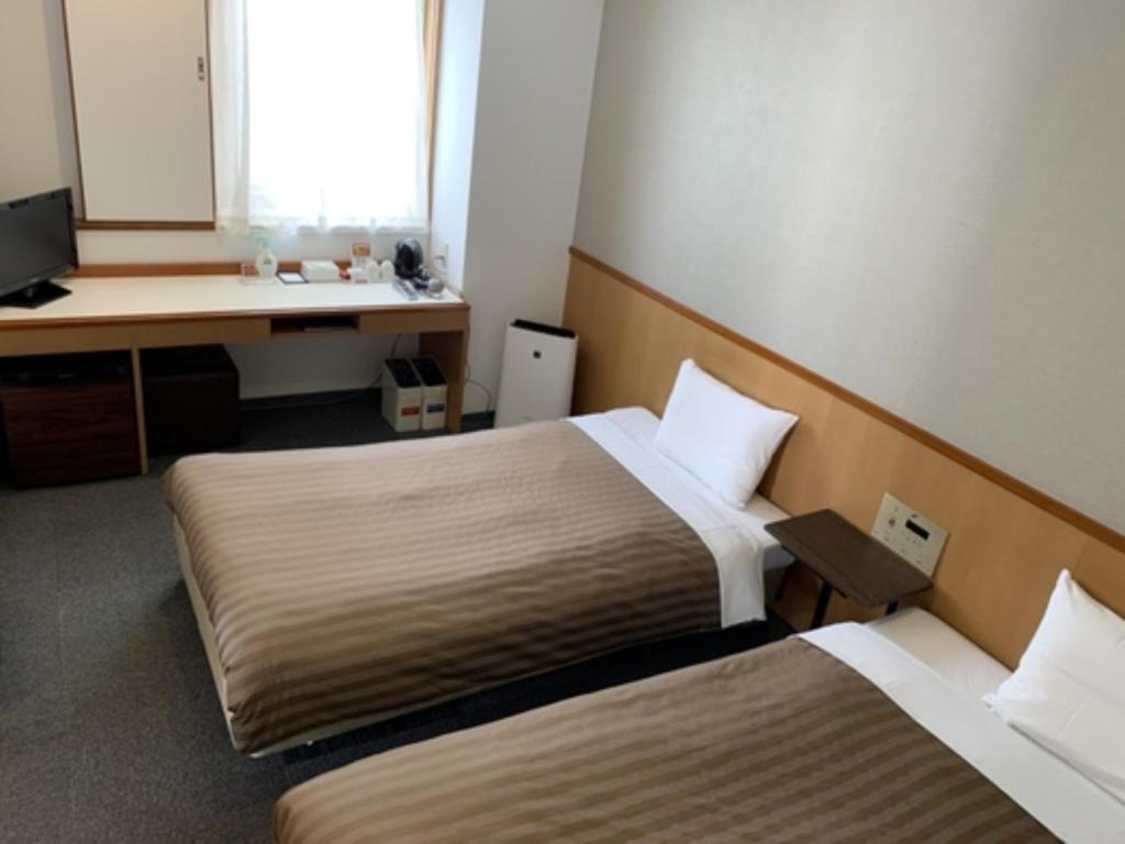 a hotel room with two beds and a desk at Hotel Axia Inn Kushiro - Vacation STAY 67230v in Irifunechō
