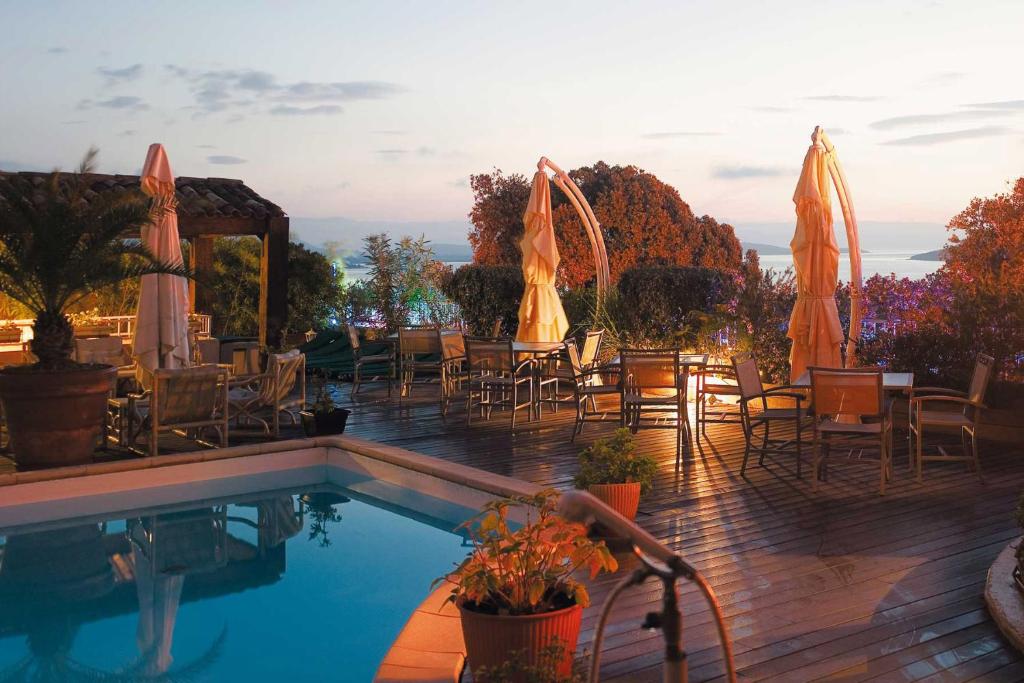 a swimming pool with tables and chairs and umbrellas at Hotel Le Tilbury in Porto-Vecchio