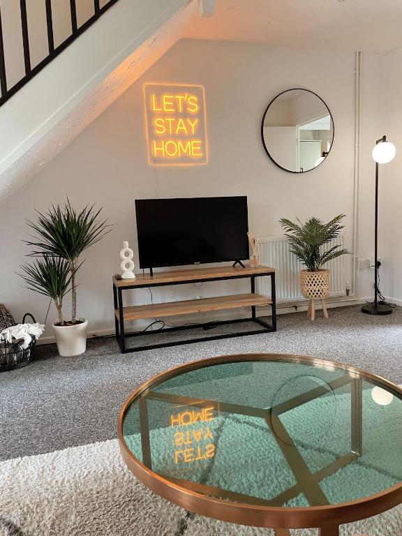 uma sala de estar com uma televisão e uma mesa de vidro em Cosy & stylish home from home em Peterborough