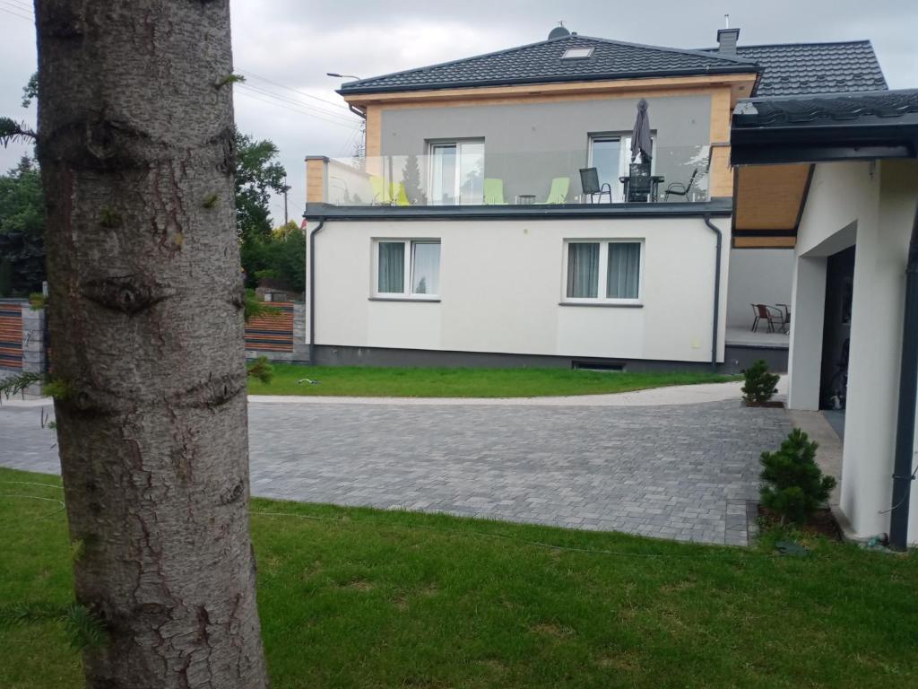 a white house with a tree in front of it at Apartament 4U - Azyl Arkadia in Suwałki