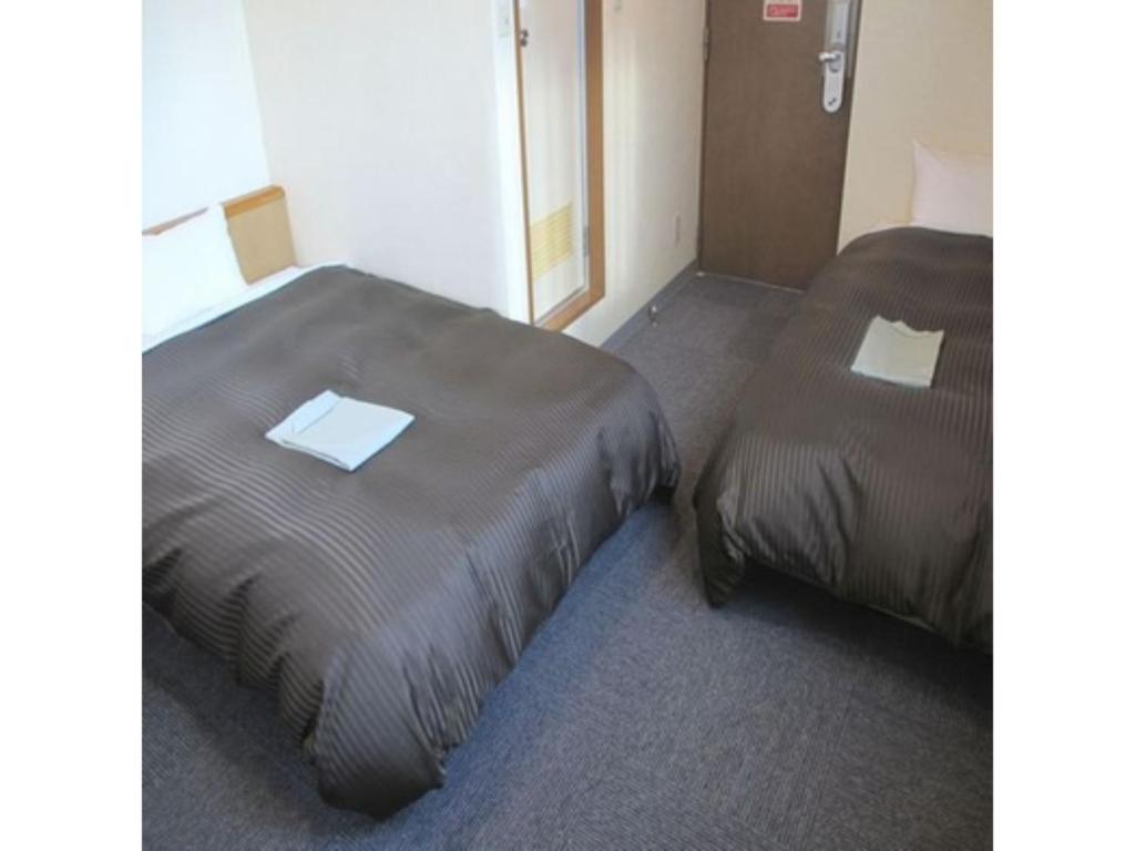 2 Betten nebeneinander in einem Zimmer in der Unterkunft Hotel Axia Inn Kushiro - Vacation STAY 67221v in Irifunechō