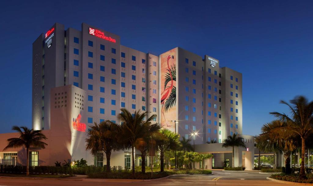 a hotel building with palm trees in front of it at Homewood Suites by Hilton Miami Dolphin Mall in Miami