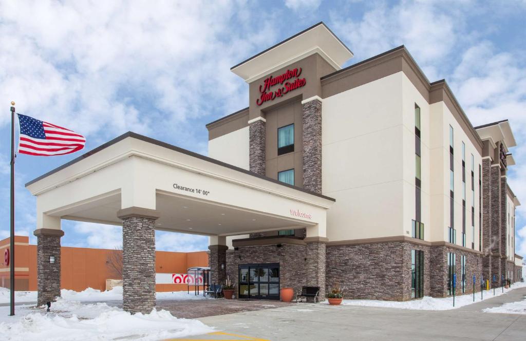 an exterior view of a hotel with an american flag at Hampton Inn & Suites Sioux City South, IA in Sioux City