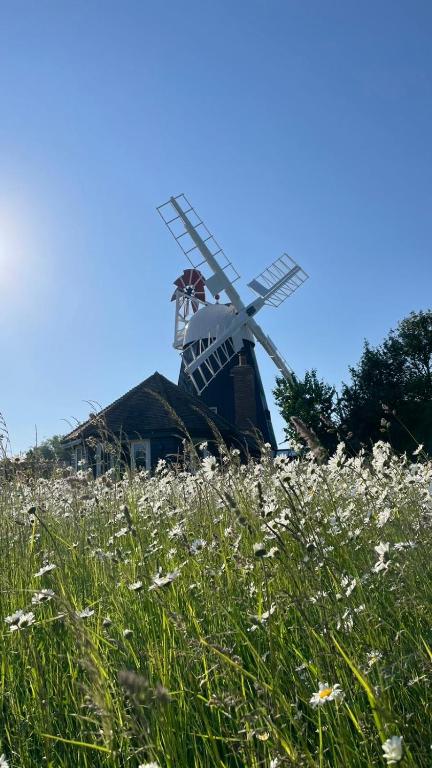 a windmill sitting on top of a field of flowers at The Millers Cottage in Cambridge