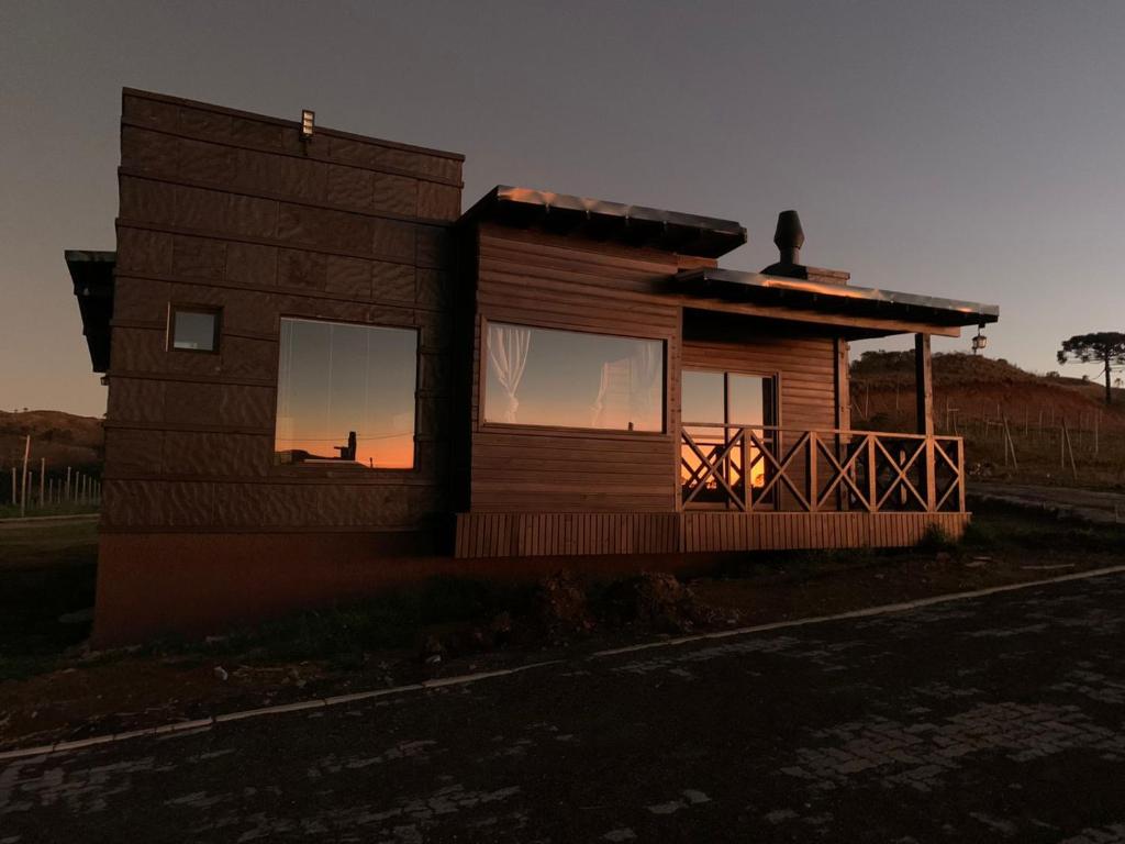 una pequeña casa con una puesta de sol en la ventana en Vinícola D'alture - Cabana Familiar en São Joaquim