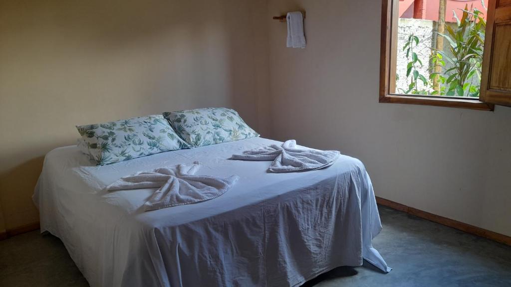 a bedroom with a bed with white sheets and a window at Pousada Mar de Mamoã in Ilhéus