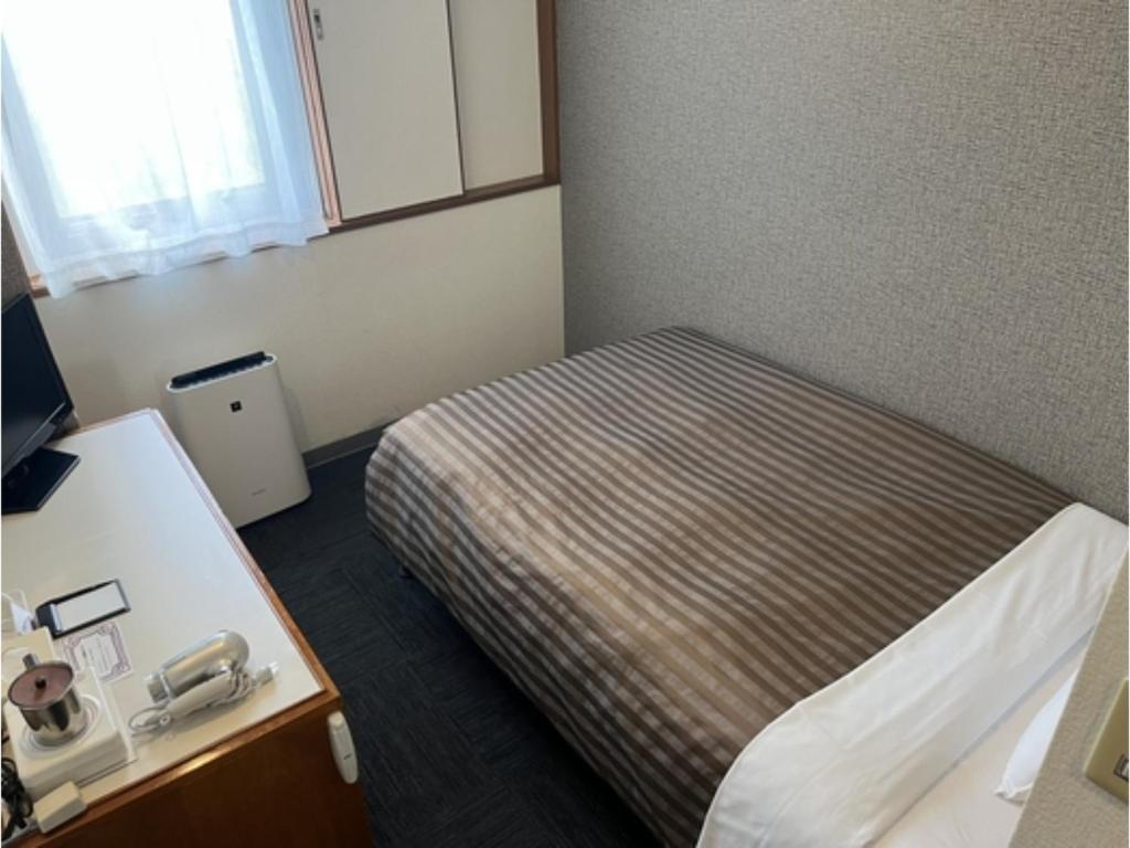 mały pokój z łóżkiem i telefonem w obiekcie Hotel Axia Inn Kushiro - Vacation STAY 67207v w mieście Irifunechō