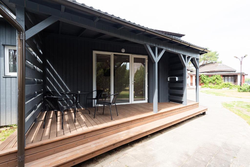 a black house with a wooden deck at Paukšcių takas Vertikalė poilsio namai in Šventoji