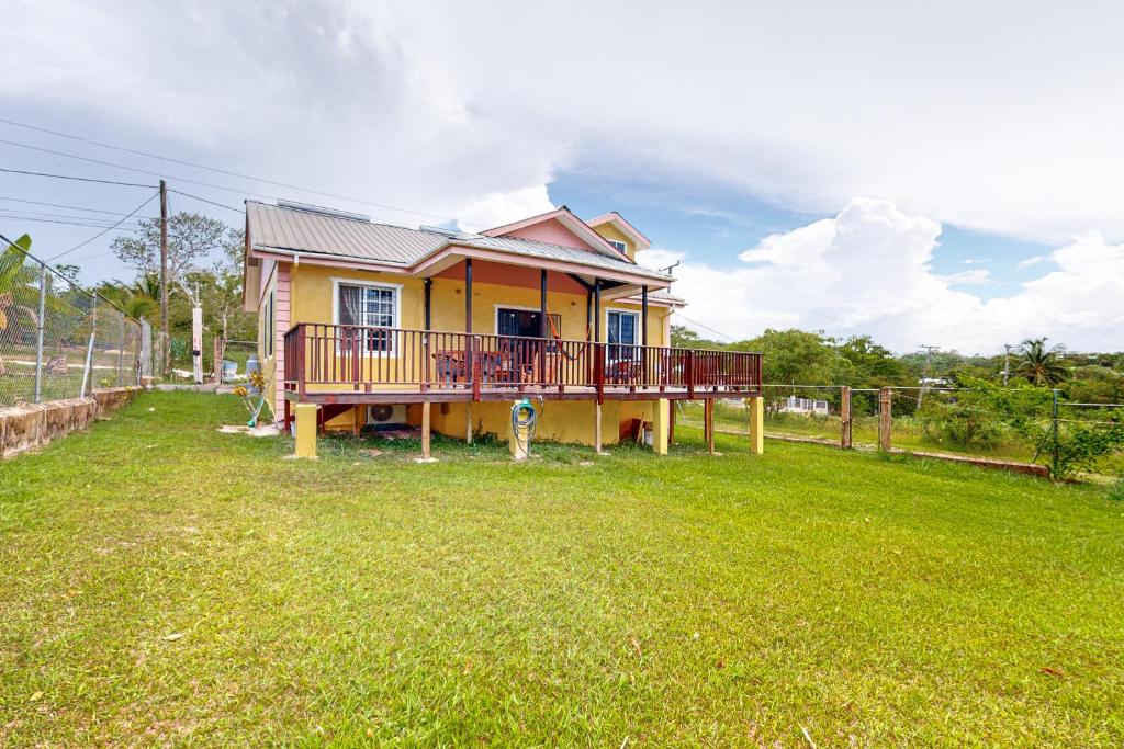 a yellow house with a deck on a yard at The Pine Tree Villa in San Ignacio