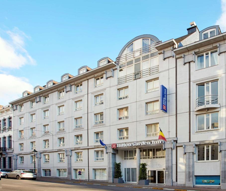 un grand bâtiment blanc au coin d'une rue dans l'établissement Hilton Garden Inn Brussels City Centre, à Bruxelles