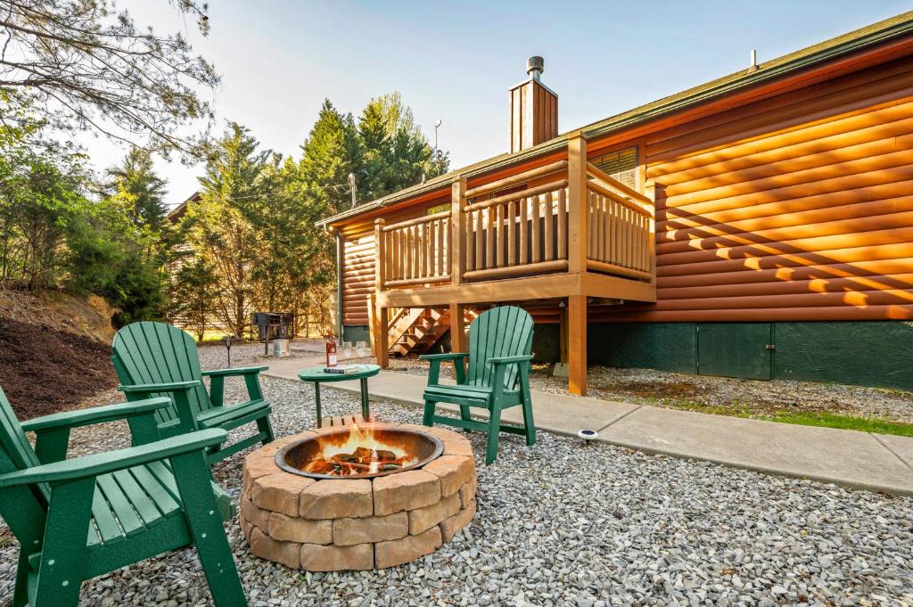 two green chairs and a fire pit in front of a house at EASY LIVIN - SECLUDED FAMILY LOG CABIN in Sevierville