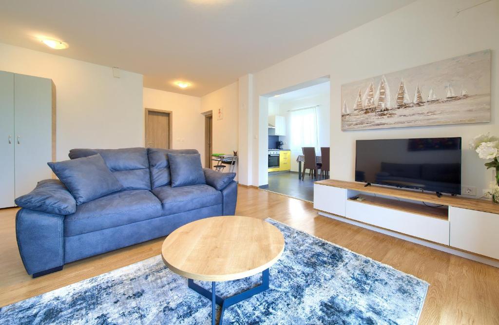 ein Wohnzimmer mit einem blauen Sofa und einem Tisch in der Unterkunft Apartments Val Njivice in Njivice