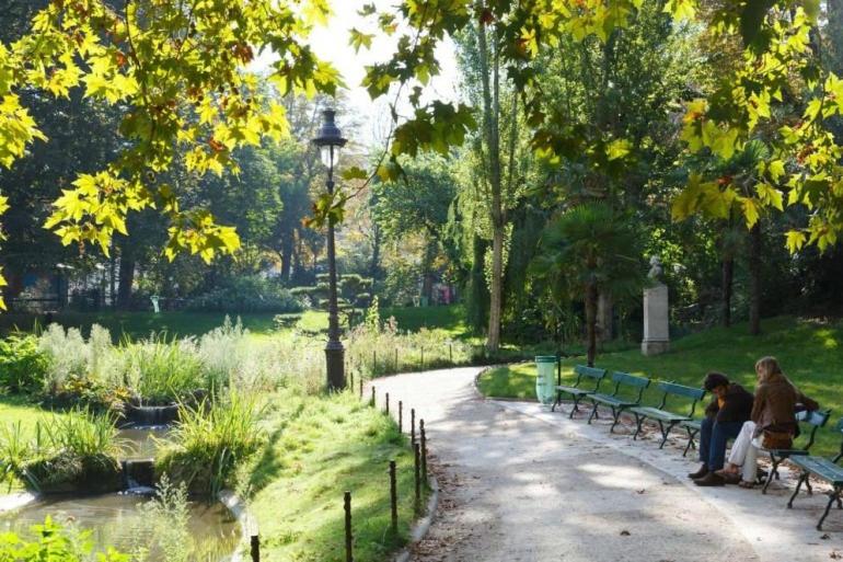 duas pessoas sentadas em bancos num parque em Paris: Appartement Batignolles em Paris