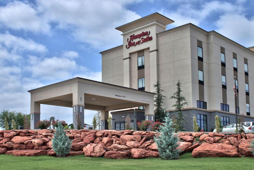 a hotel building with a rock wall in front of it at Hampton Inn & Suites Guthrie, OK in Guthrie
