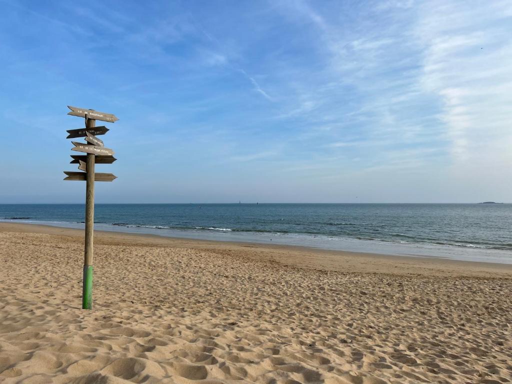 a wooden sign on a beach with the ocean at Villa en bord de mer in Pornichet