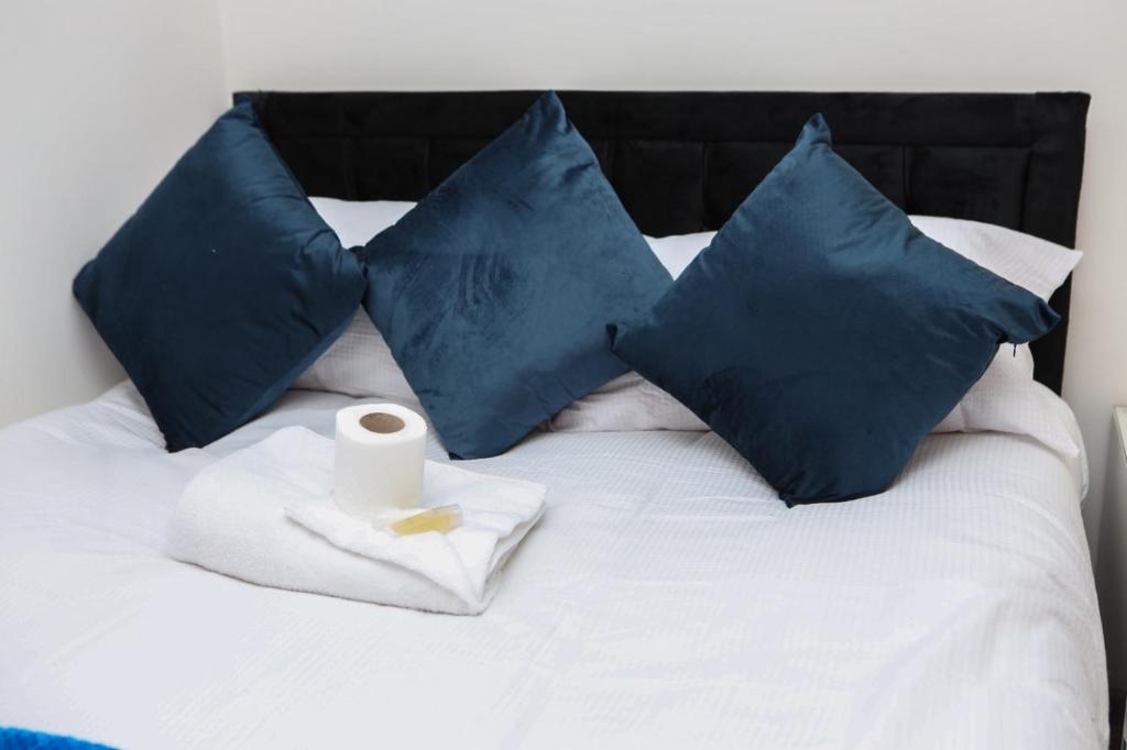 a bed with blue pillows and a towel and a roll of toilet paper at CHATHAM GUEST HOUSE in Chatham